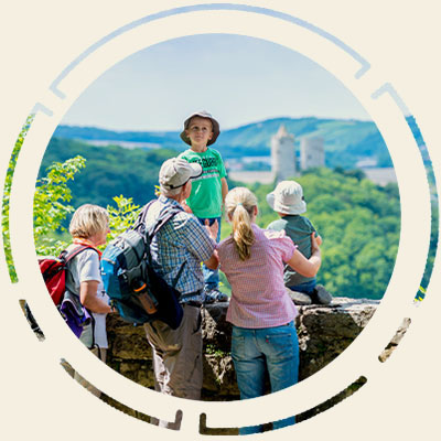 Eine Familie mit Kindern sehen sich aus der Ferne eine Burg an.